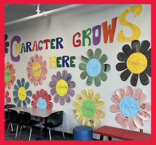 The words Character Grows Here, with some large paper flowers on the wall